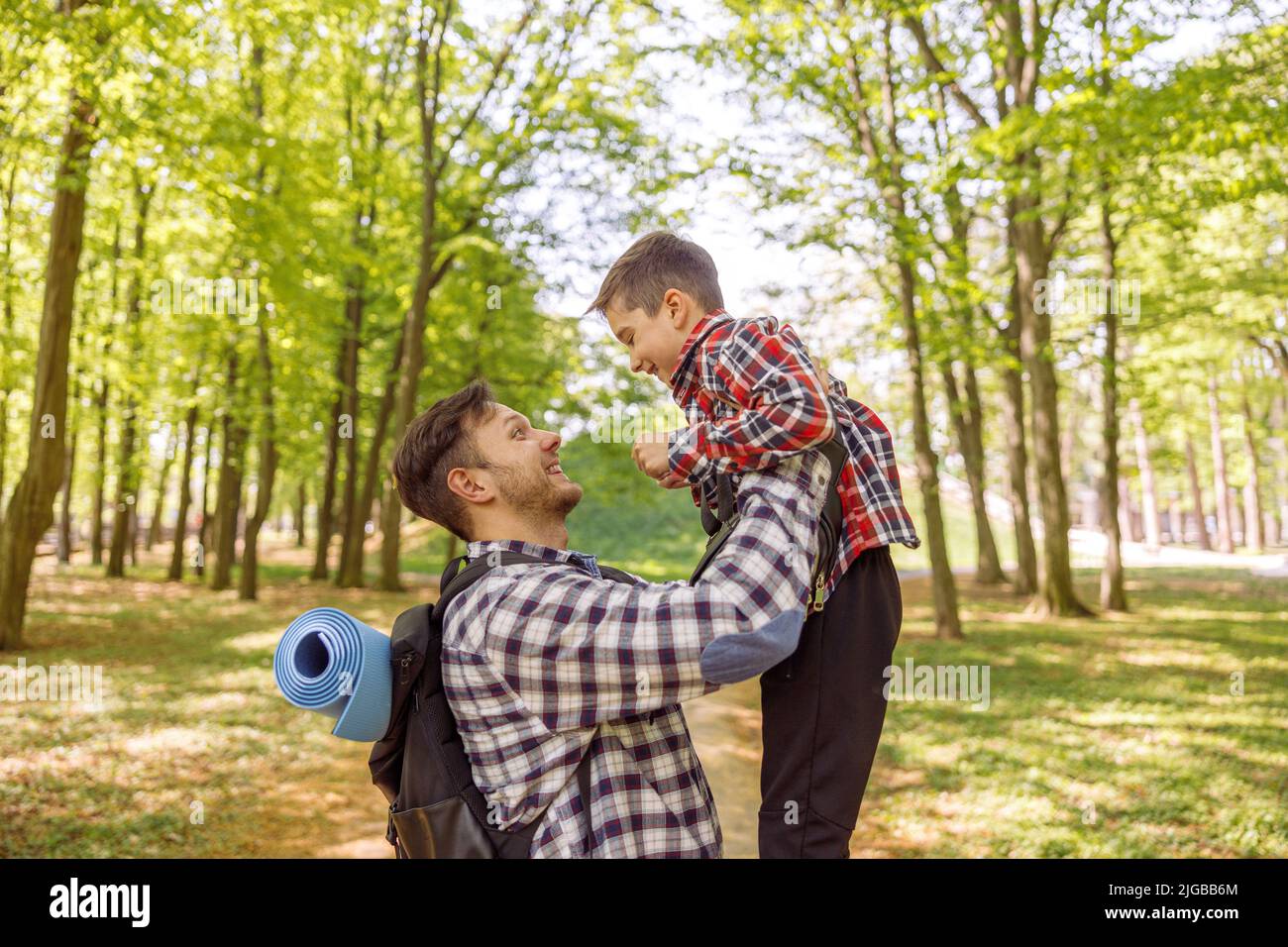 Fröhlicher kaukasischer Mann, der seinen kleinen niedlichen Sohn in den Händen hoch hält. Aufsteigendes Kind. Im Wald. Stockfoto