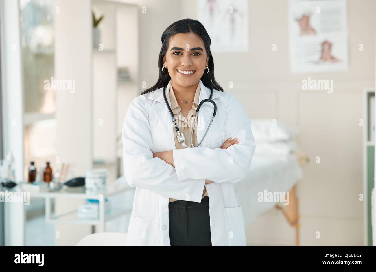 Eine attraktive junge Ärztin, die allein in ihrer Klinik steht und ihre Arme gefaltet hat. Stockfoto