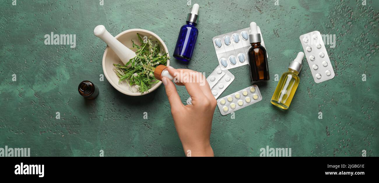 Frau, die auf pflanzlicher Basis Medikamente auf grünem Hintergrund, Draufsicht Stockfoto