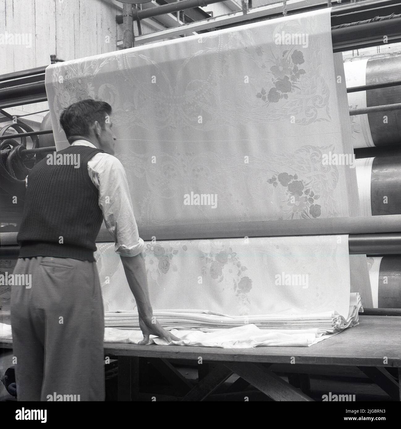 1950s, historisch, ein männlicher Agent, der die Herstellung von Leinenrollen überwacht, Nordirland, Großbritannien. Leinen ist ein natürliches Textil, das aus den Fasern der Flachspflanze hergestellt wird, die natürlich in Irland wächst und für eine Vielzahl von alltäglichen Materialien wie Tischdecken, Servietten und Bettdecken sowie Kleidung verwendet wird. Stockfoto