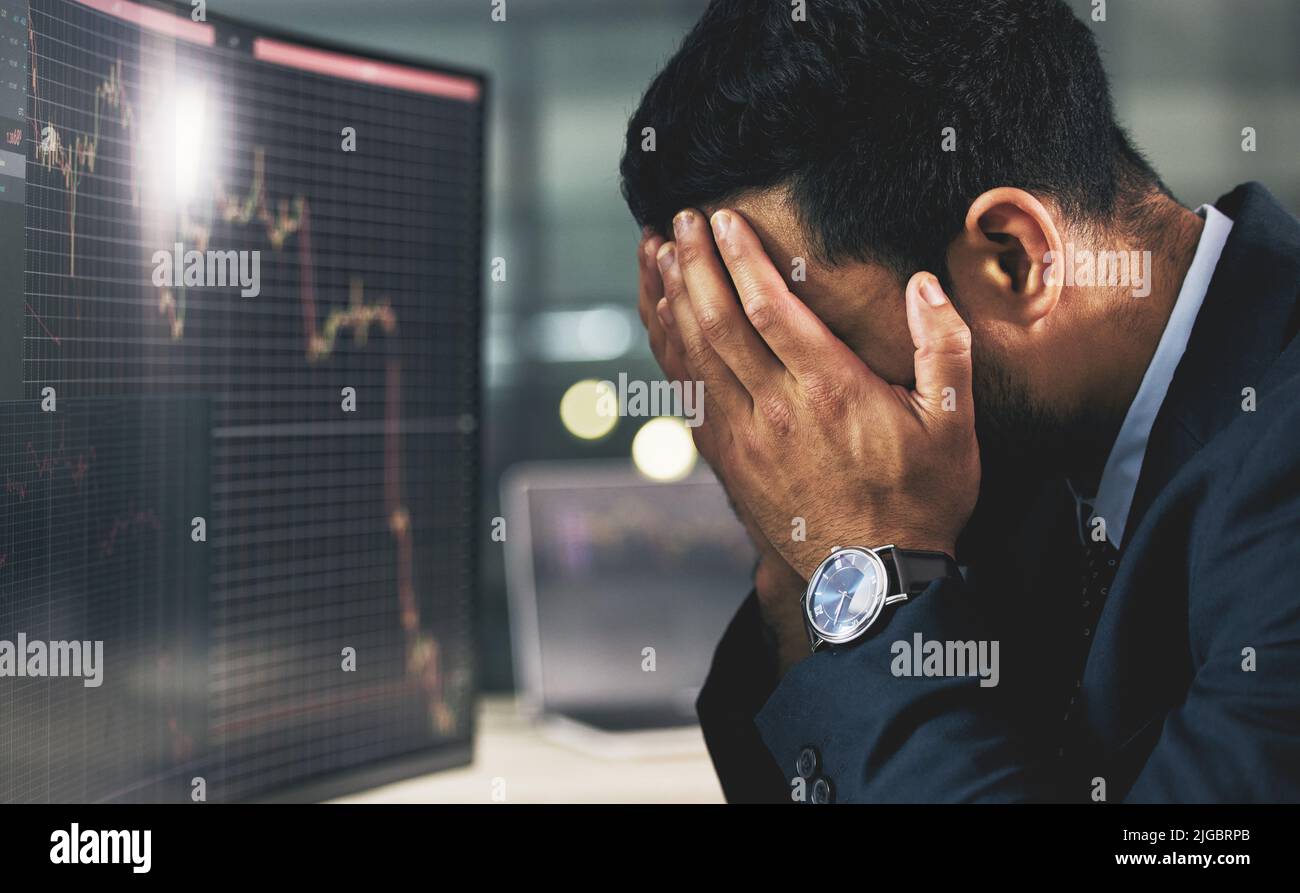 Der phönix muss brennen, um aufzutauchen. Ein junger Börsenexperte, der gestresst bei der Arbeit schaut. Stockfoto