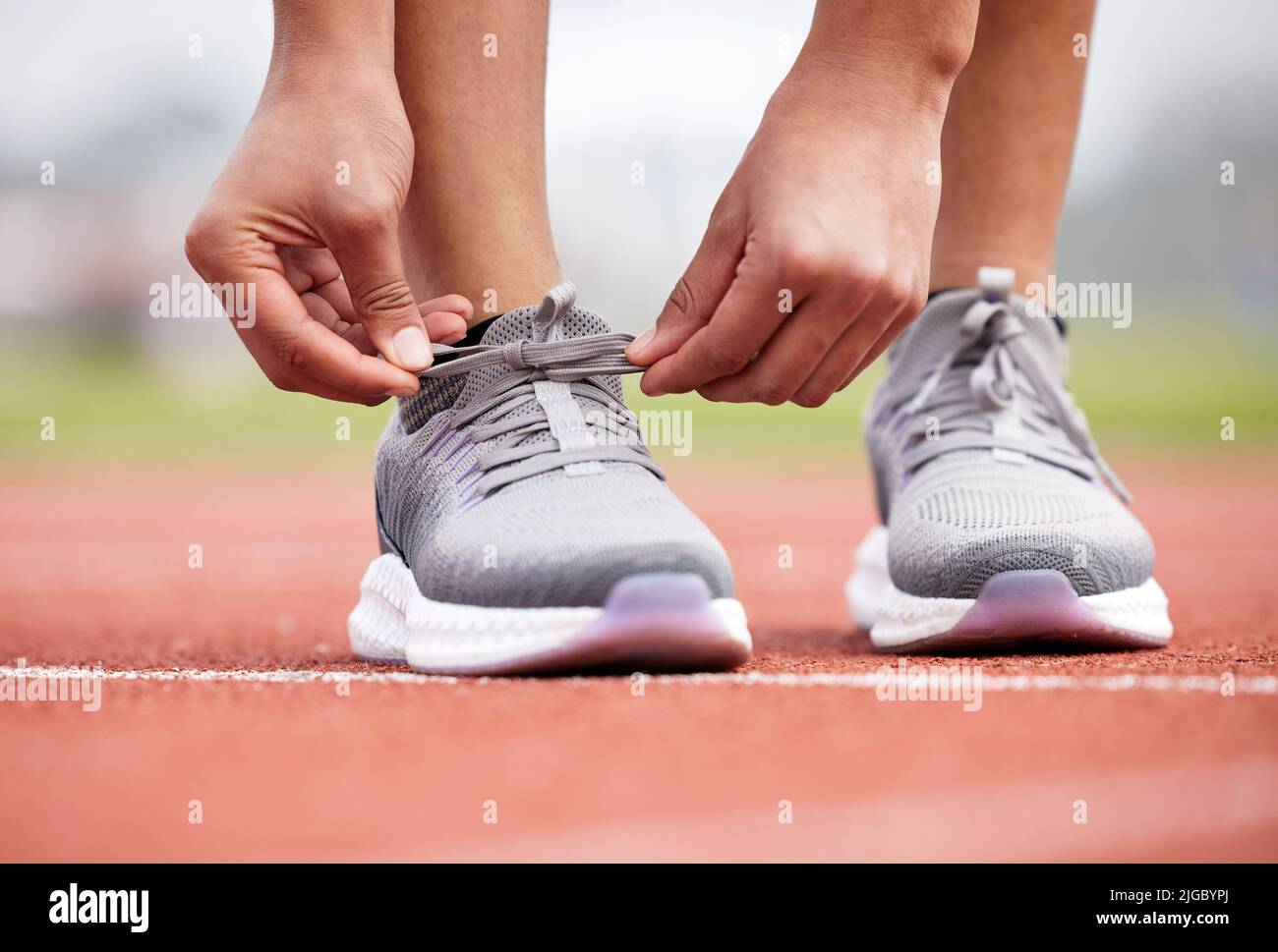 Shes Knoten in der Stimmung zu stolpern. Eine unkenntliche weibliche Athletin Band ihre Schnürsenkel auf der Strecke. Stockfoto