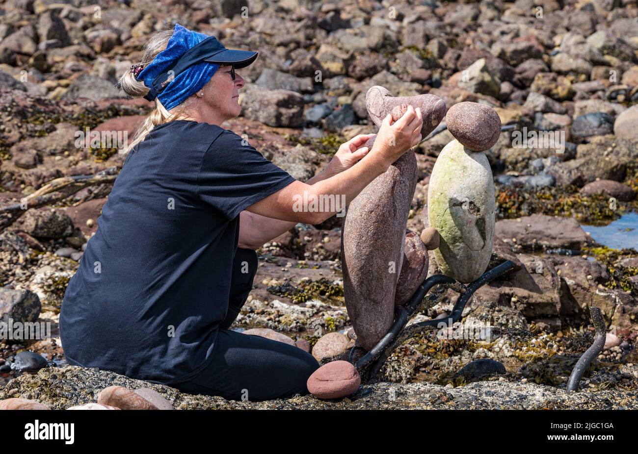 Dunbar, East Lothian, Schottland, Großbritannien, 9.. Juli 2022. European Stone Stacking Championship: Die Teilnehmer haben 3,5 Stunden Zeit, ein künstlerisches Kunstwerk aus den Felsen am Eye Cave Beach zu kreieren. Im Bild: Caroline Walker aus Edinburgh Stockfoto