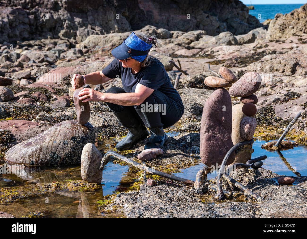 Dunbar, East Lothian, Schottland, Großbritannien, 9.. Juli 2022. European Stone Stacking Championship: Die Teilnehmer haben 3,5 Stunden Zeit, ein künstlerisches Kunstwerk aus den Felsen am Eye Cave Beach zu kreieren. Im Bild: Caroline Walker aus Edinburgh Stockfoto