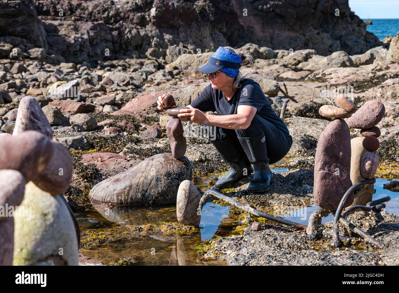 Dunbar, East Lothian, Schottland, Großbritannien, 9.. Juli 2022. European Stone Stacking Championship: Die Teilnehmer haben 3,5 Stunden Zeit, ein künstlerisches Kunstwerk aus den Felsen am Eye Cave Beach zu kreieren. Im Bild: Caroline Walker aus Edinburgh Stockfoto