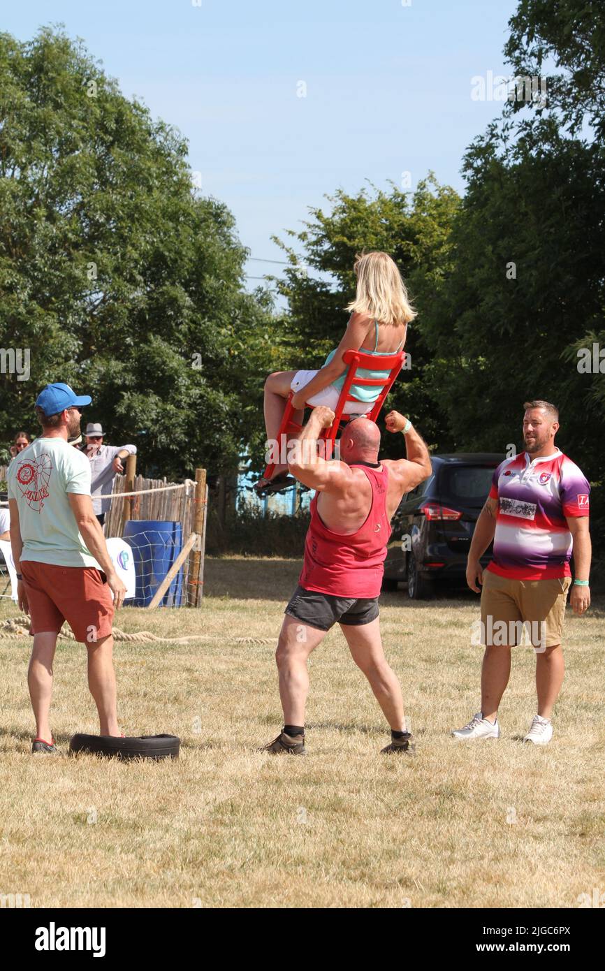 Lawford, Großbritannien. 09.. Juli 2022. Die Tendring Hundred Show ist die wichtigste Landwirtschaftsmesse in Essex. Adrian Smith, bekannt als Mighty Smith, ist ein dreifacher Gewinner des stärksten Mannwettbewerbs Großbritanniens. Hier hält er das volle Gewicht einer Dame, die auf einem Stuhl an den Zähnen sitzt. Kredit: Eastern Views/Alamy Live Nachrichten Stockfoto