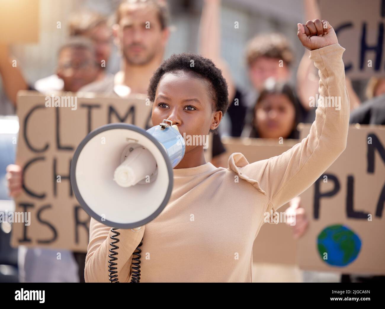 Sie werden unsere Stimmen hören. Eine junge Frau, die bei einem Protest durch ein Megaphon spricht. Stockfoto