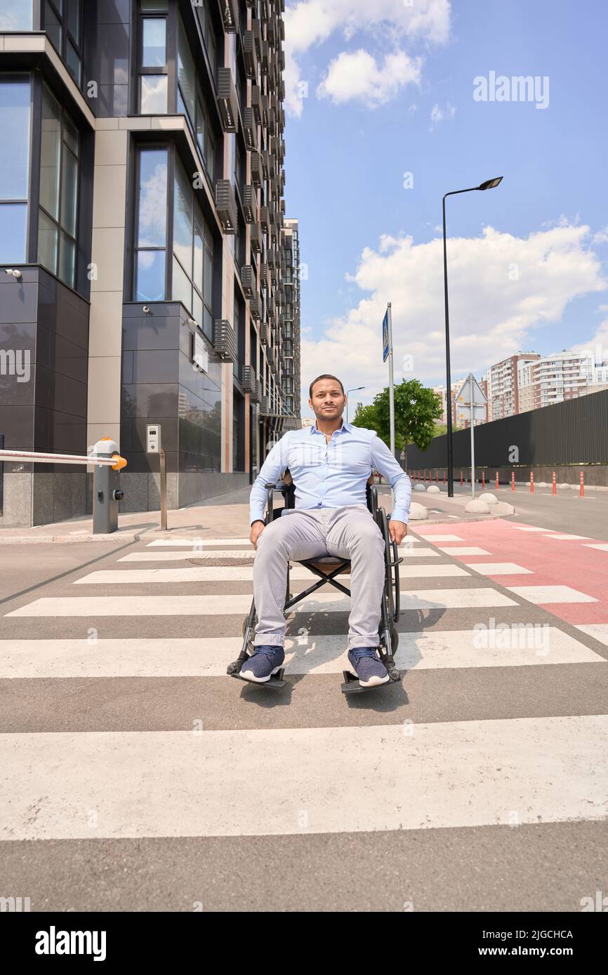 Behinderter Mann im manuellen Rollstuhl auf Zebraüberquerung Stockfoto