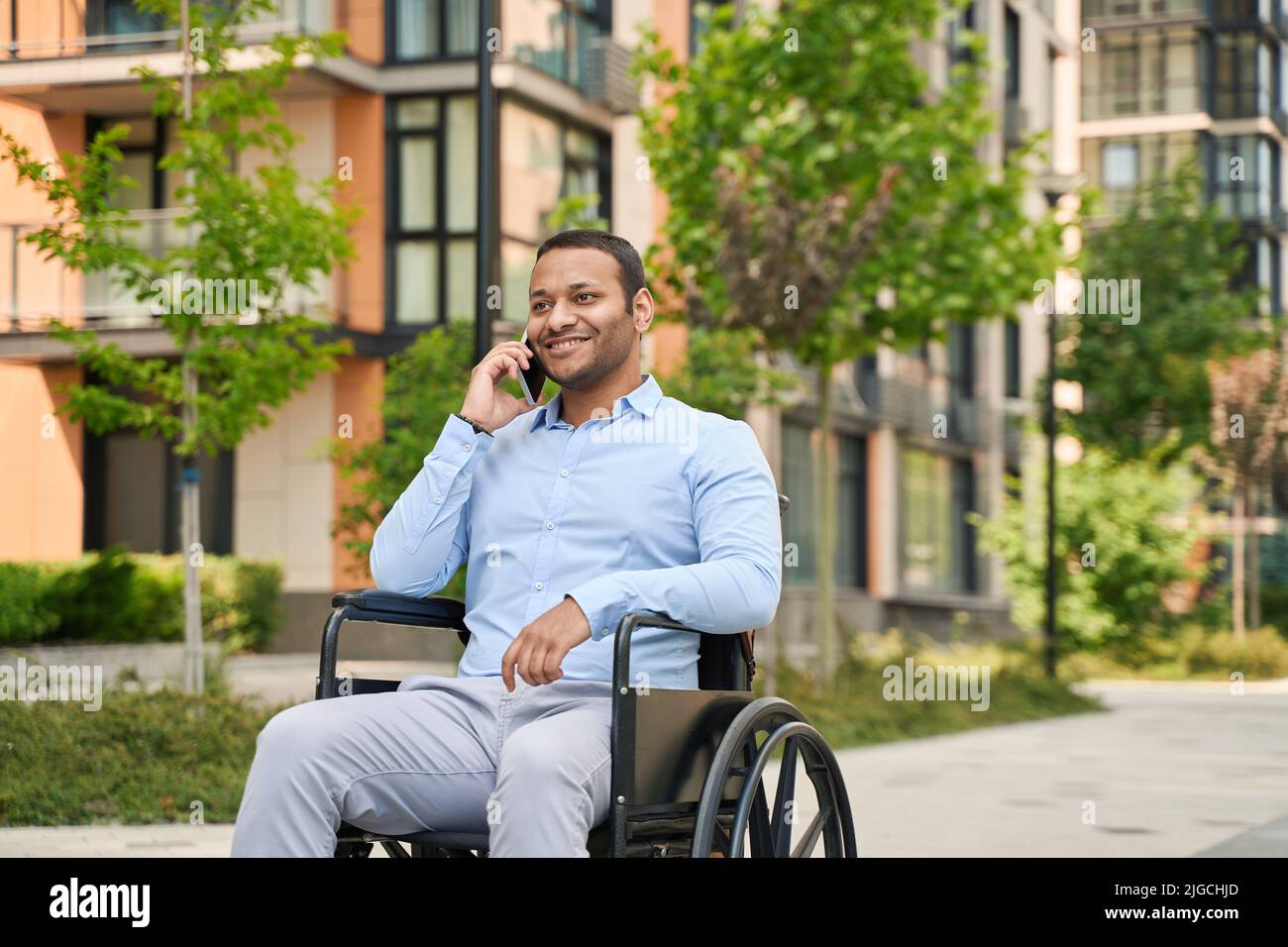 Fröhlicher, behinderter Mann, der sich am Handy unterhielt Stockfoto