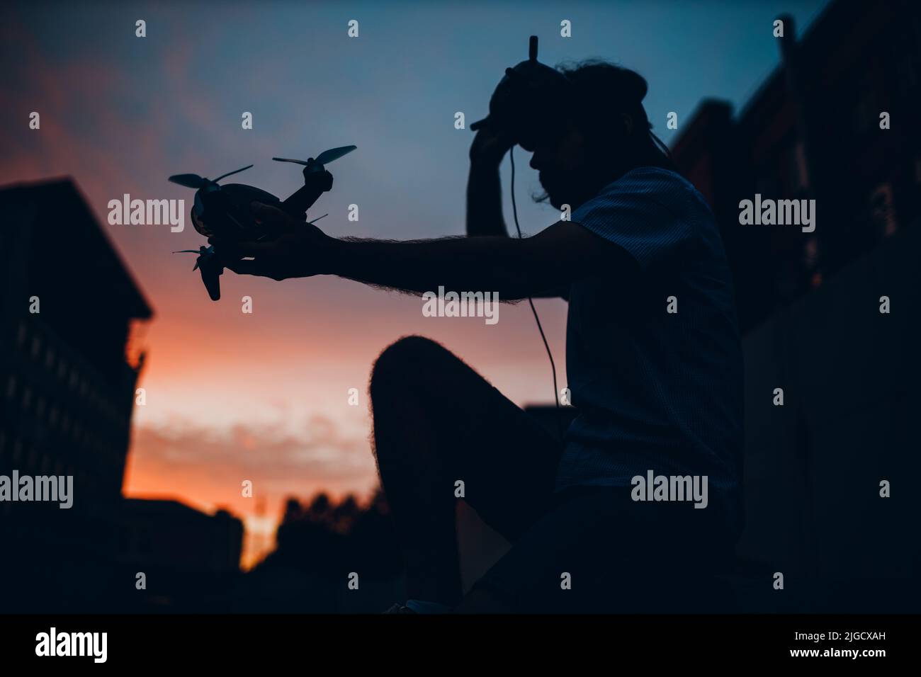 Mann Pilot sitzen Silhouette starten Quadcopter Drohne Quad Stadt Stockfoto