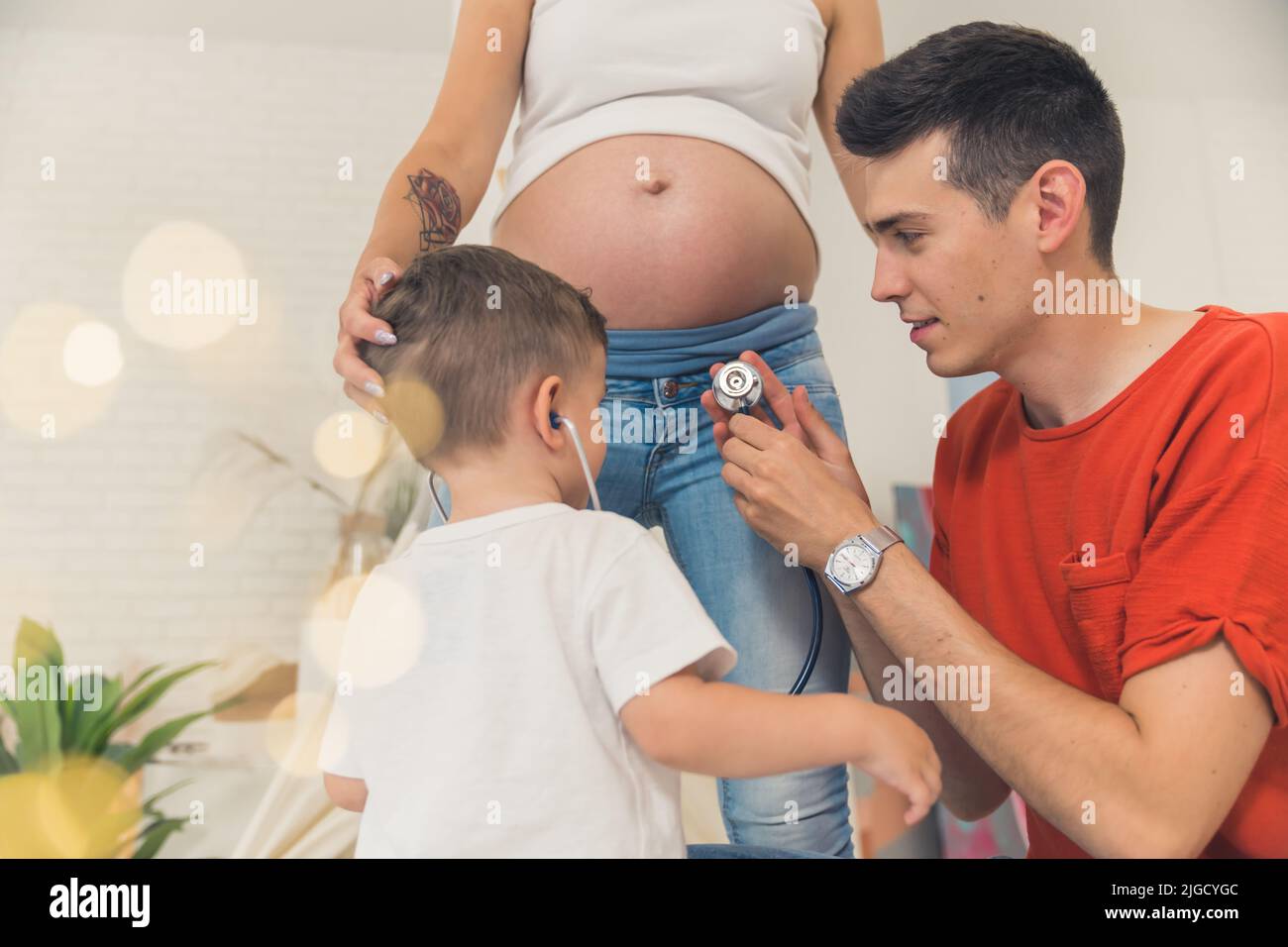 Ein junger Mann, der seinem Sohn dabei hilft, dem Herzschlag eines Babys im Bauch seiner glücklichen Familie zuzuhören. Hochwertige Fotos Stockfoto