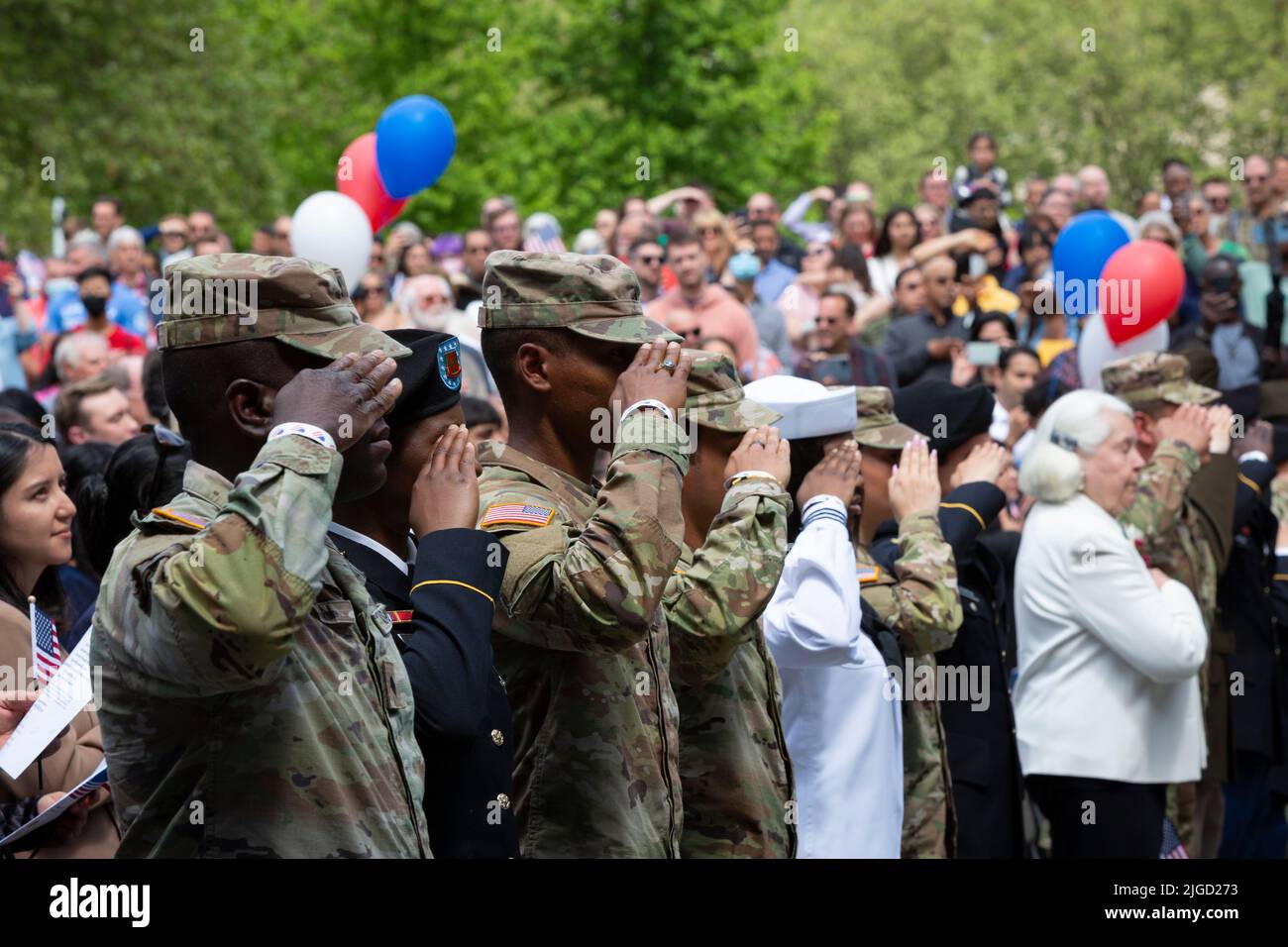 Mitglieder des US-Militärs und Kandidaten für die US-Staatsbürgerschaft grüßen die Farbkontrollbeamten, die während eines Einbürgerungskrieges Flaggen auf die Bühne bringen Stockfoto