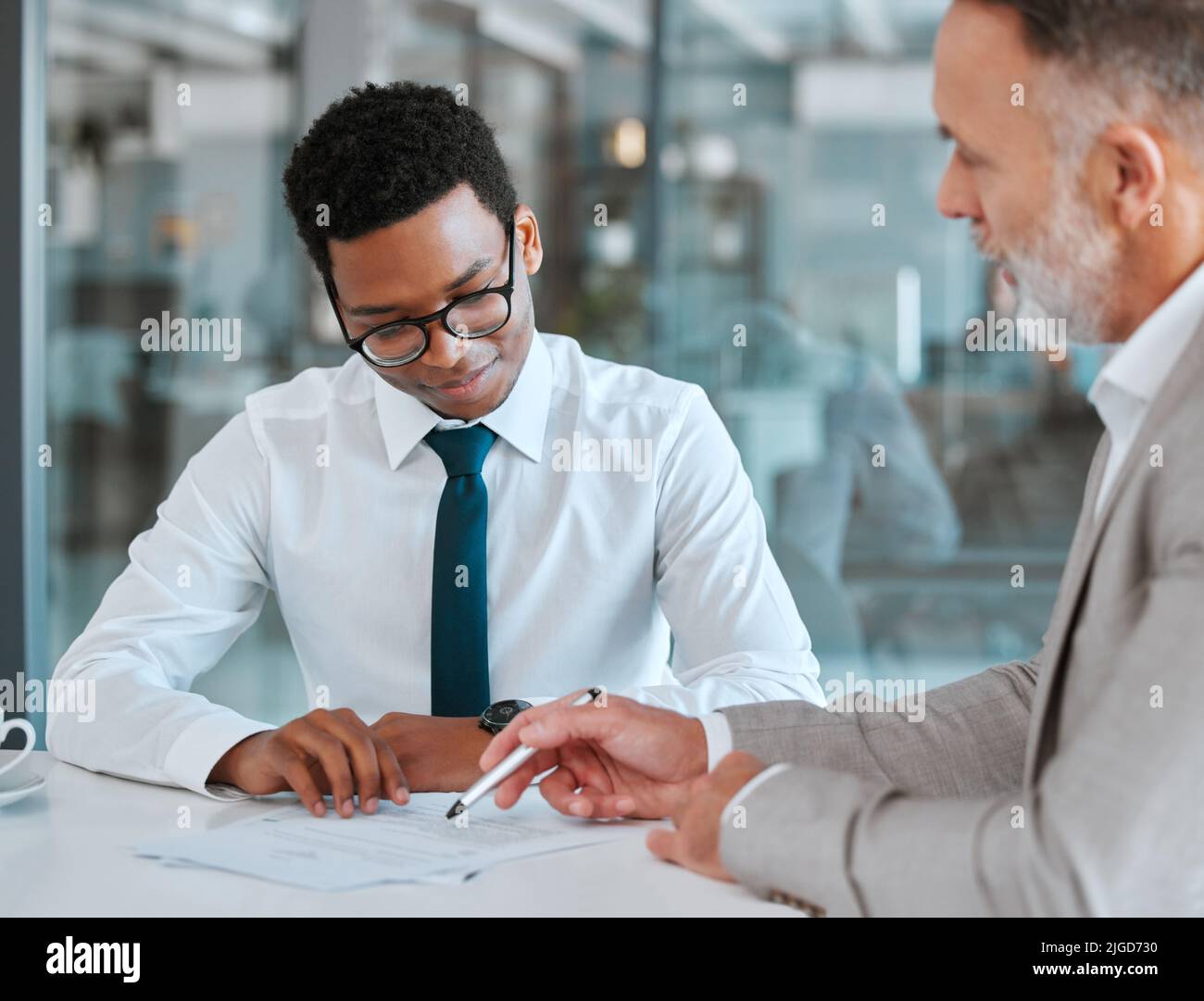 Die Gewohnheit des Sparens ist selbst eine Ausbildung. Zwei Geschäftsleute, die einen Vertrag in einem Büro unterzeichnen. Stockfoto