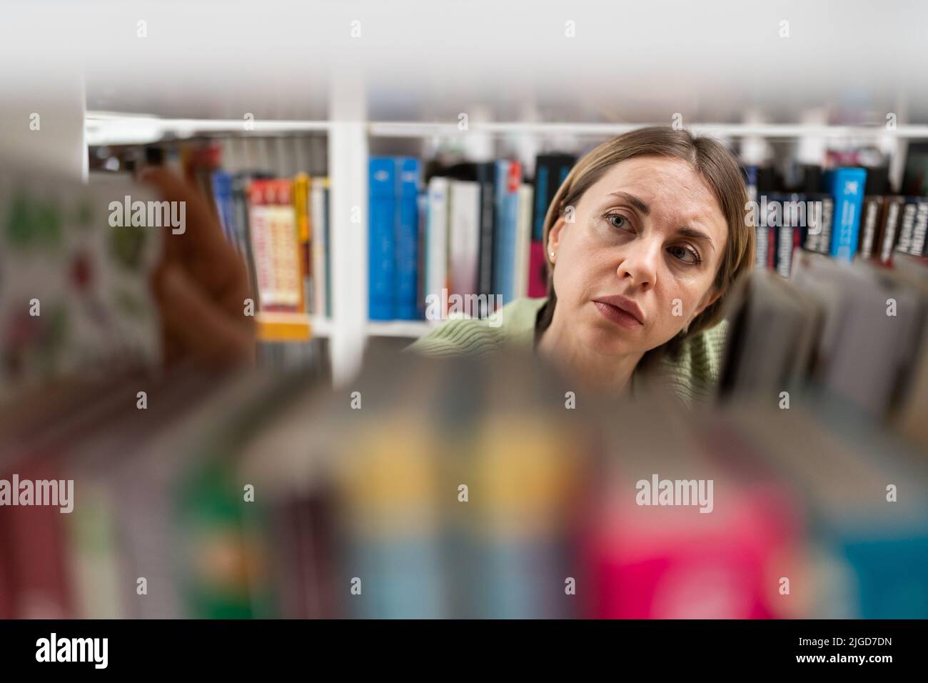 Frauen mittleren Alters wählen Buch aus Bücherregal in der Hochschule, Universitätsbibliothek für Bildungsforschung Stockfoto