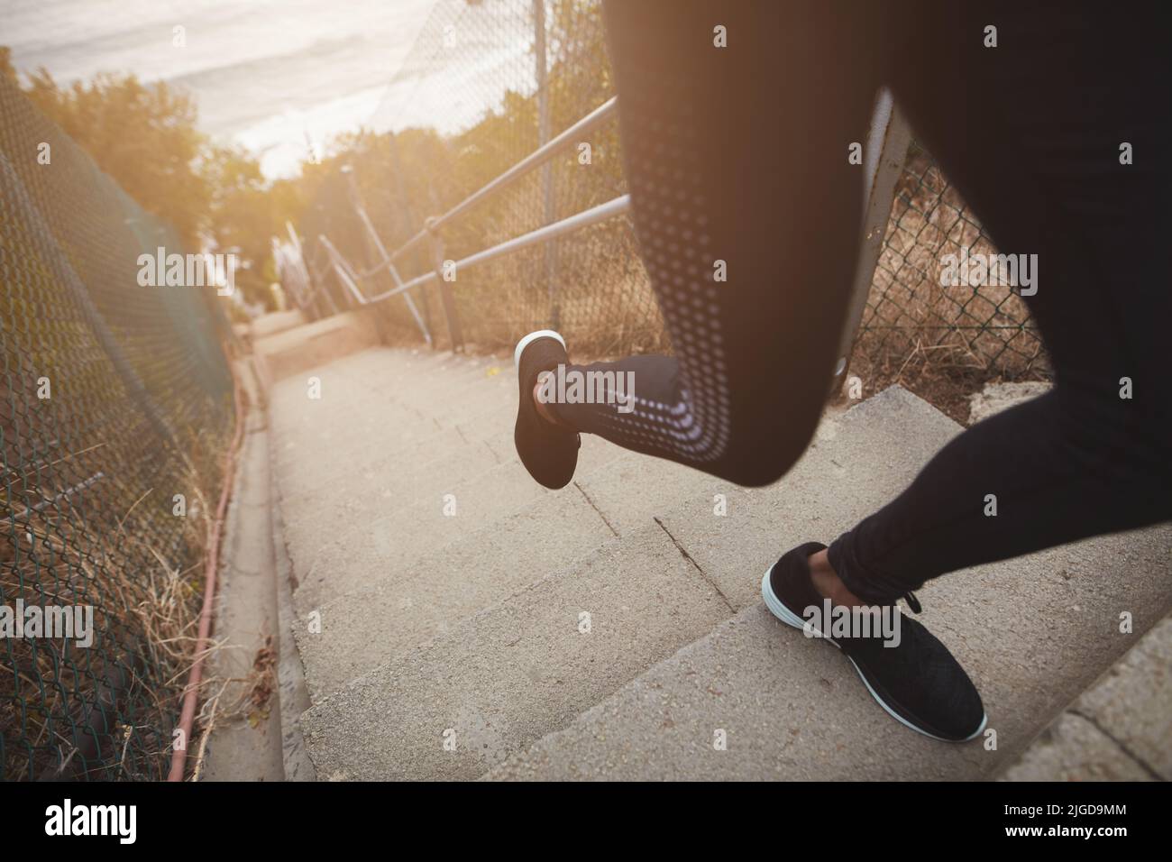 Nahaufnahme einer Läuferin, die zur Übung Schritte hochläuft. Konzentrieren Sie sich auf die Beine der Frau beim Training auf der Treppe im Freien. Stockfoto