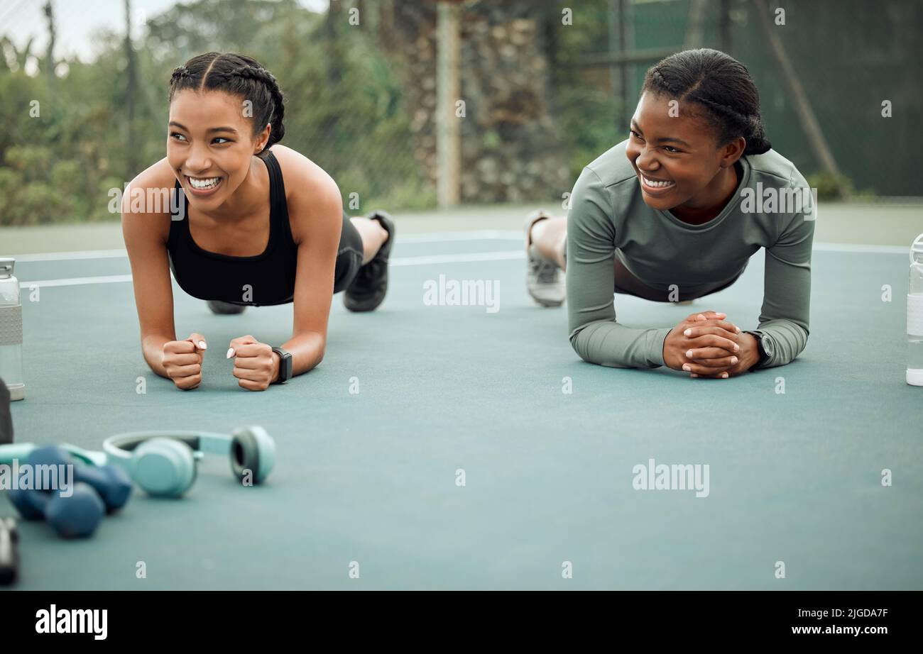 Mal sehen, wer aushalten kann. Ganzkörperaufnahme von zwei attraktiven jungen Sportlerinnen, die beim Sport auf einem Sportplatz planken. Stockfoto
