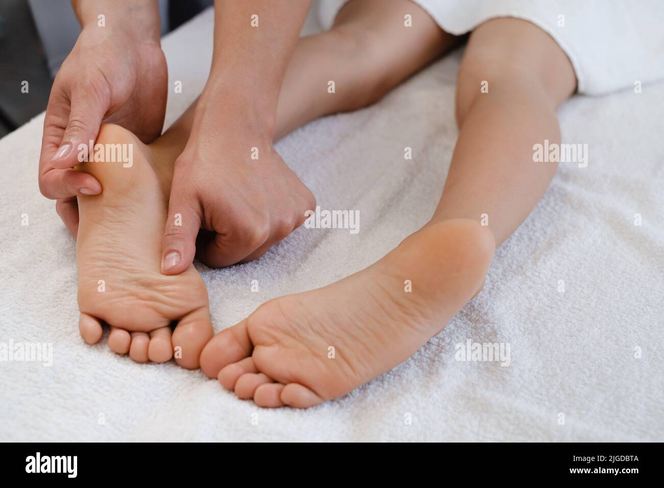 Fußmassagebehandlung für Kinder durch professionellen Masseur im Spa-Resort. Wellness, Stressabbau und Verjüngungskonzept Stockfoto