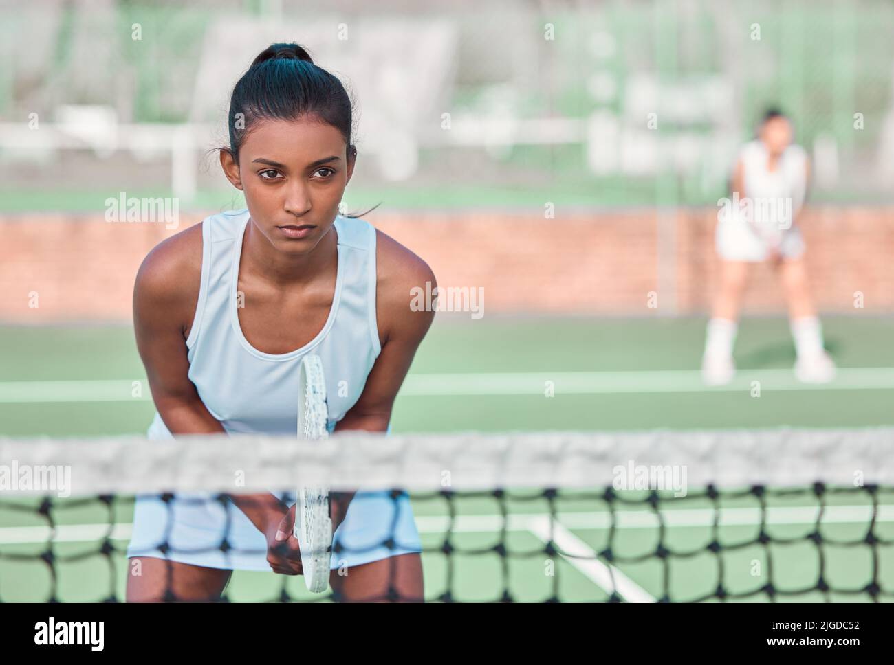 Ein Profi weiß alles darüber, voll konzentriert zu bleiben. Eine sportliche junge Frau spielt Tennis auf einem Platz. Stockfoto