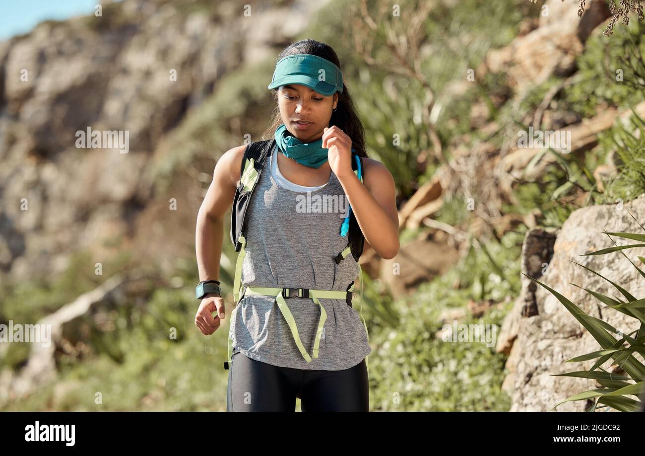 Jeder Trail wird Sie herausfordern. Eine junge Frau, die auf einem Trail auf dem Berg läuft. Stockfoto