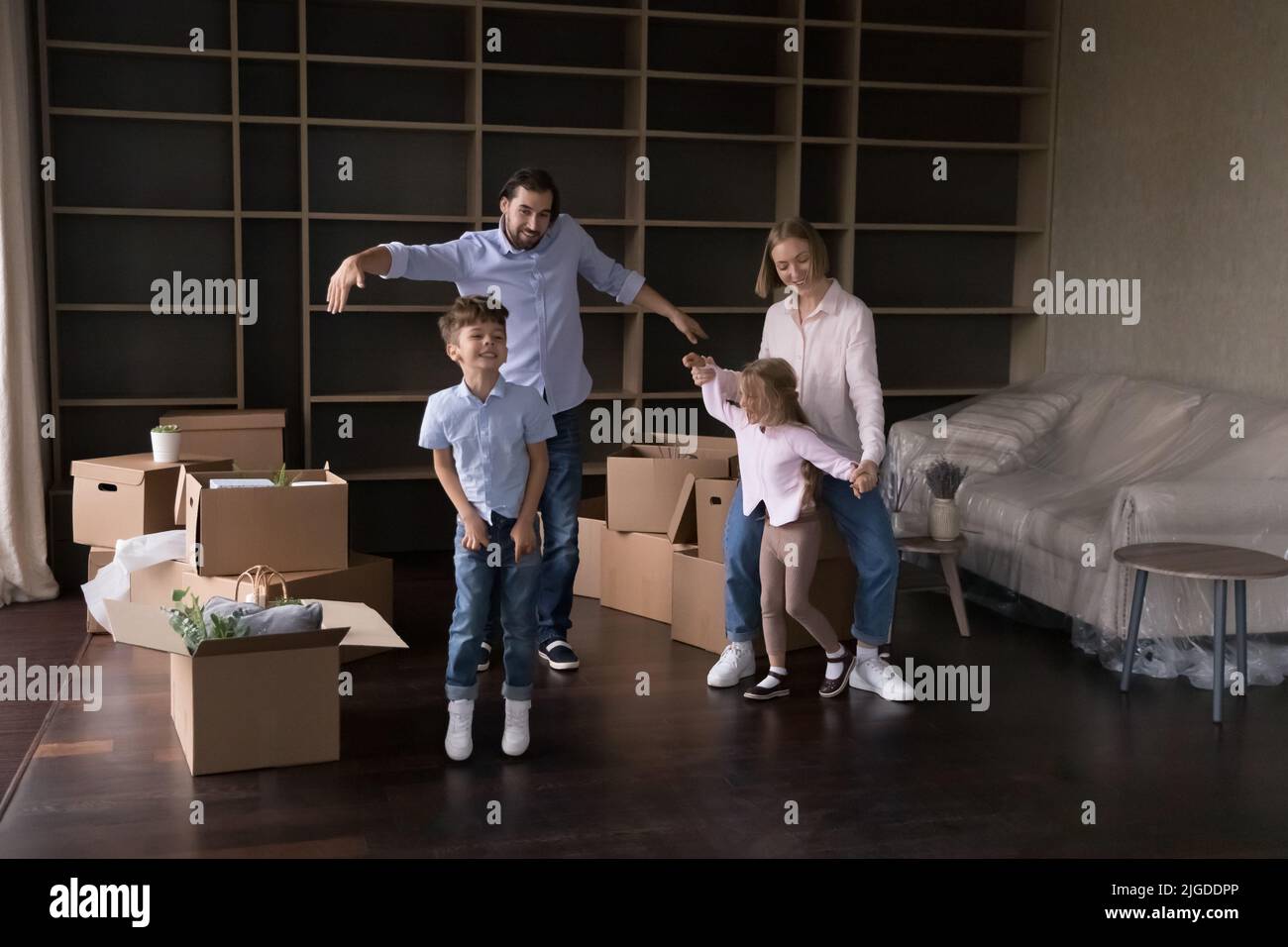 Glückliche aktive Eltern lehren zwei energische Kinder zu tanzen Stockfoto