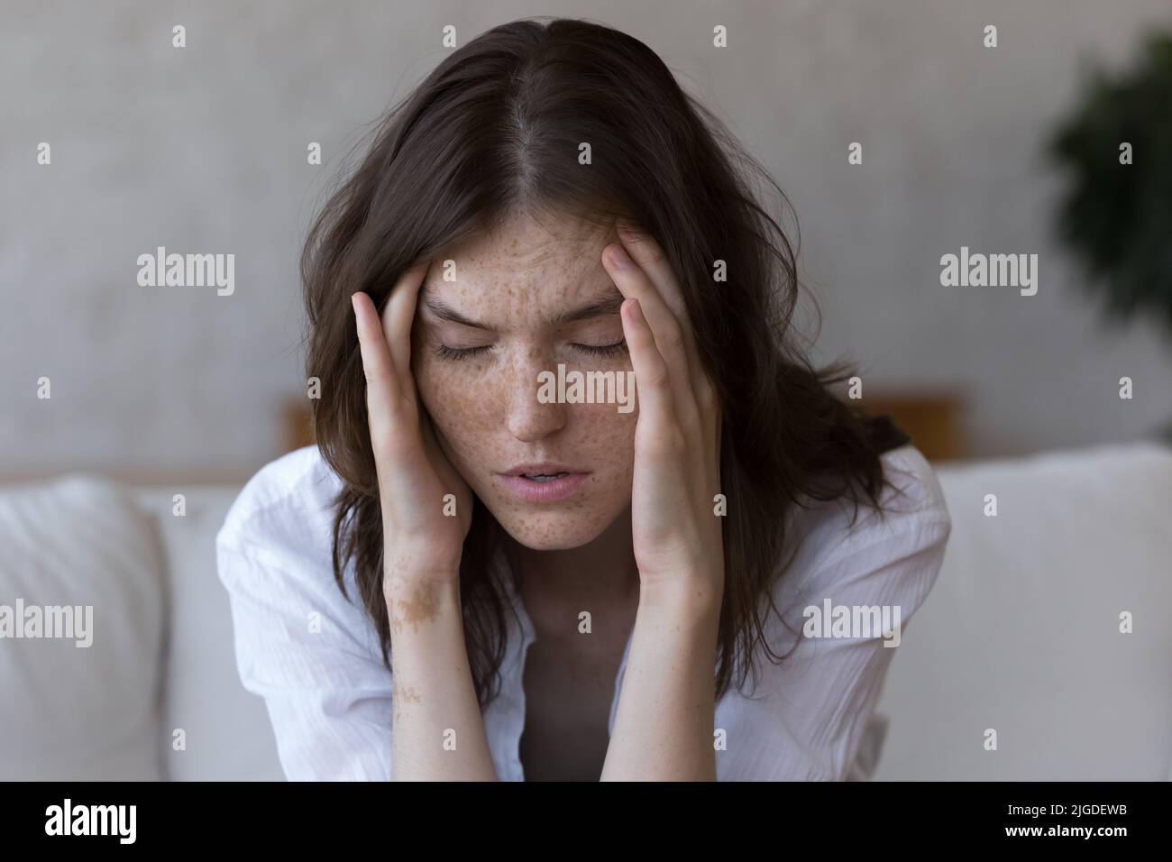 Sommersprossen Frau berührt Tempel leidet unter Kopfschmerzen fühlt sich ungesund, Nahaufnahme Stockfoto