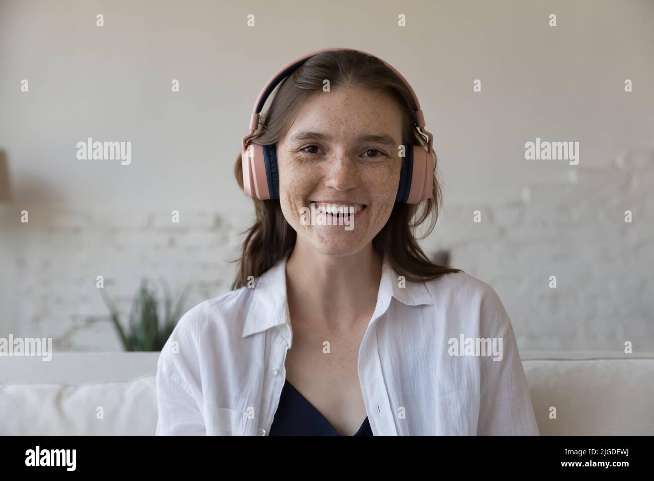 Headshot Portrait Attraktive Sommersprossen-Frau in Kopfhörern starrt auf die Kamera Stockfoto