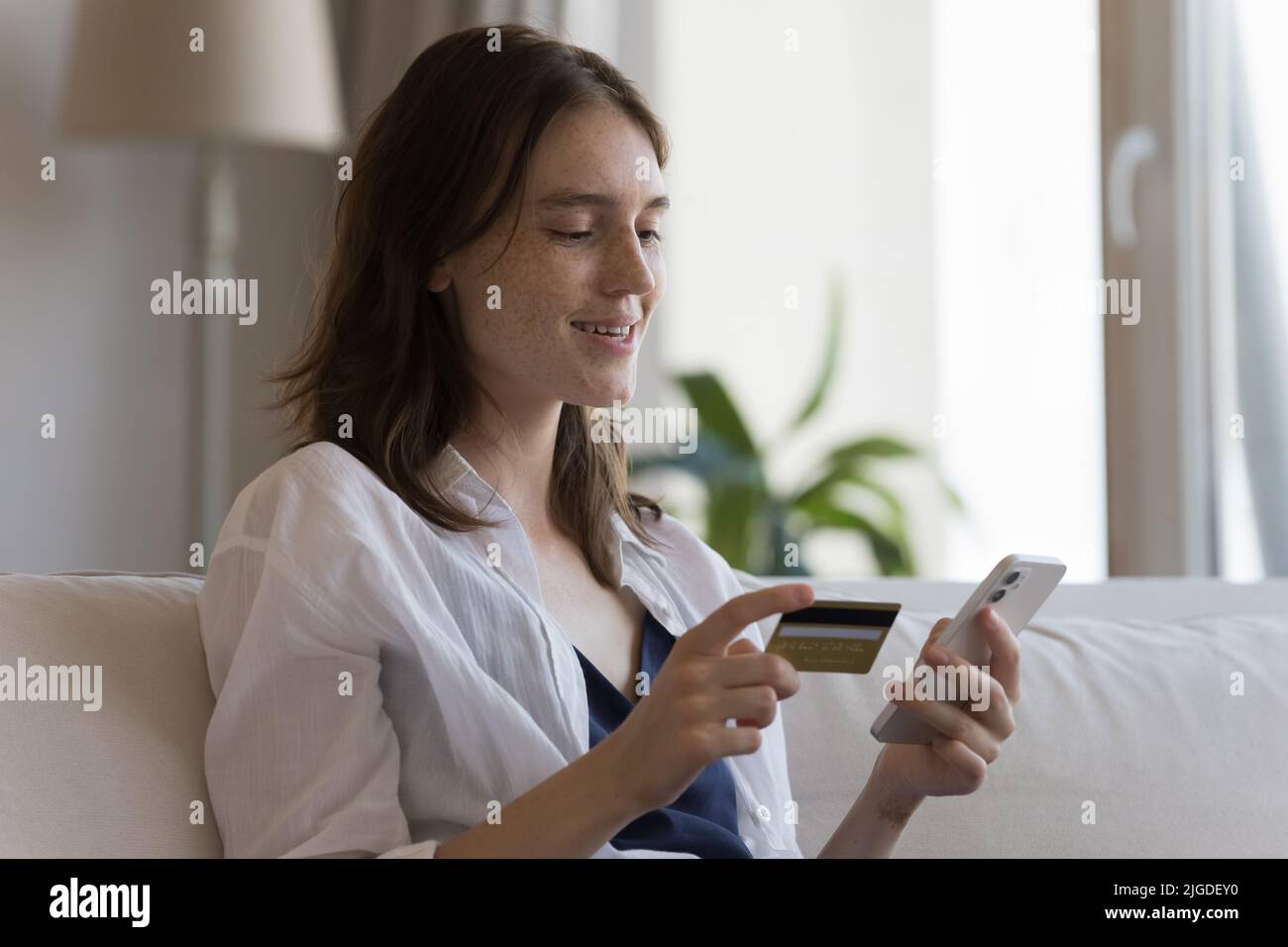 Frau hält Kreditkarte und Handy, um Waren online zu kaufen Stockfoto