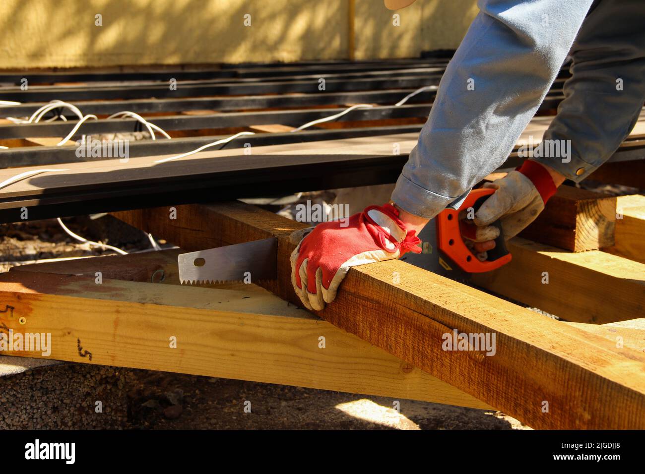 Der Auftragnehmer hält eine Handsäge, um einen Balken zu schneiden. Stockfoto