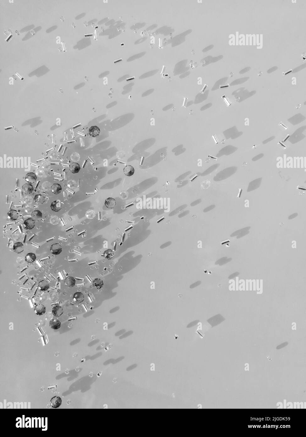 Ein Haufen Kristalle und Perlen verteilt sich über den Tisch. Nahaufnahme. Schatten auf der Oberfläche. Stockfoto