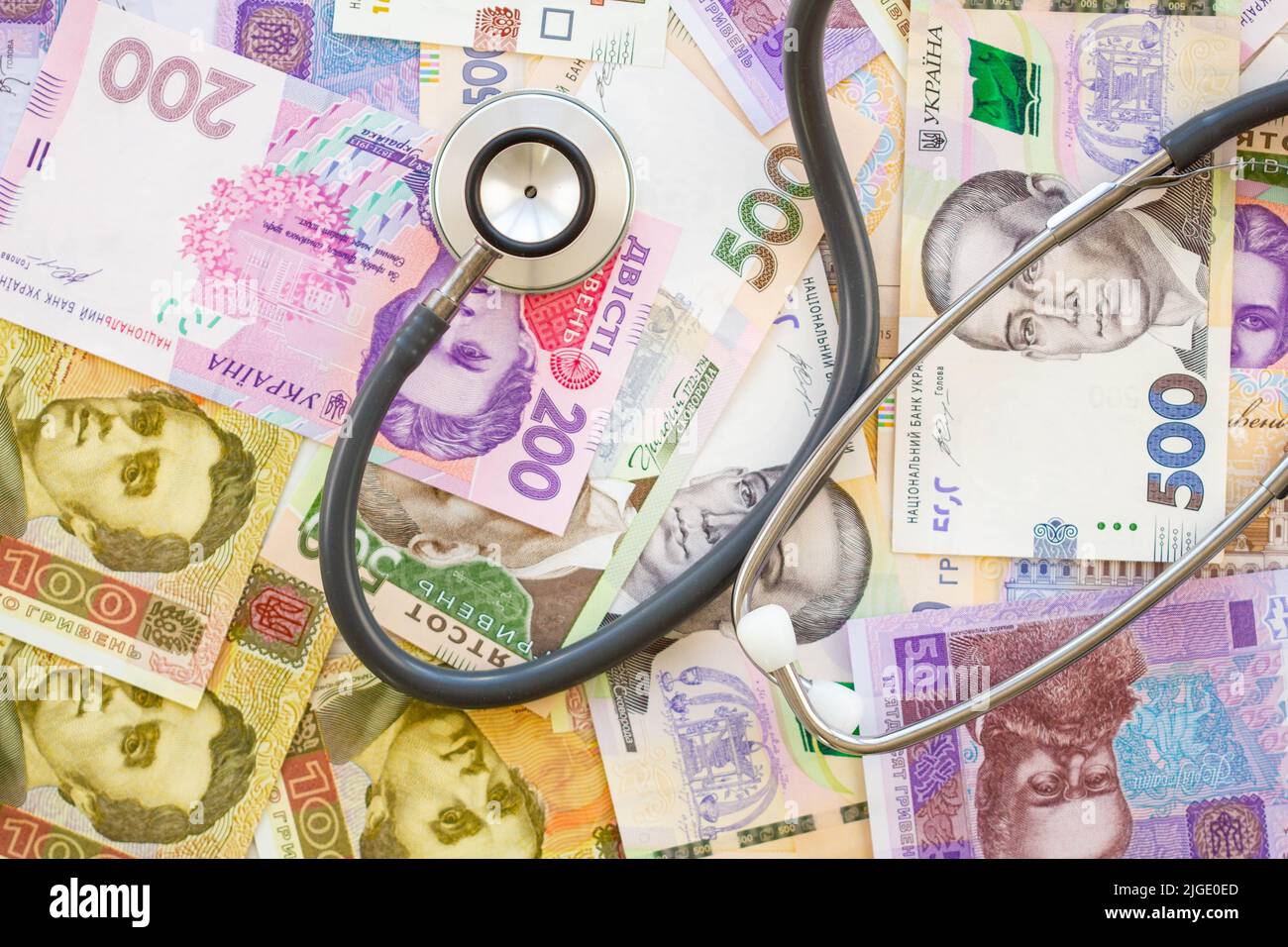 Stethoskop und Geld. Das Konzept der teuren Medizin. Ukrainische Hrywna. Viele Banknoten auf dem Tisch. Eine Menge Geld im Hintergrund. Gesundheit Stockfoto
