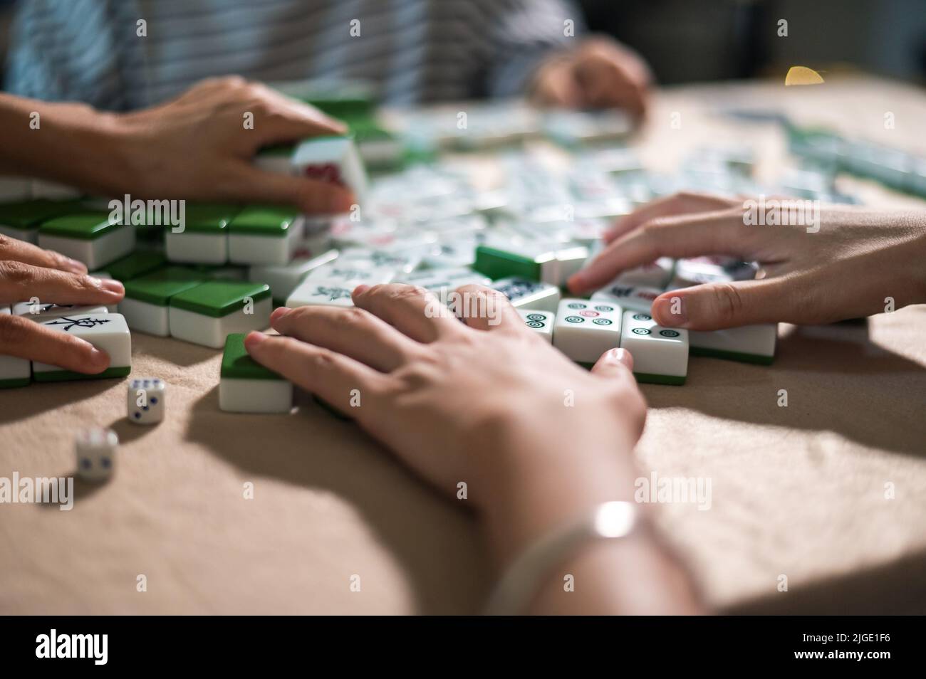 Weibliche Freunde spielen zu Hause Mahjong traditionelles chinesisches Brettspiel. Übersetzung: Kacheltext zeigt chinesische Zeichen für Zahlen von 1 bis 9 und si Stockfoto