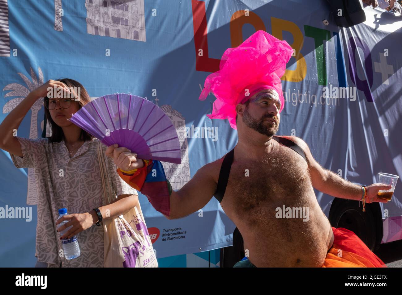 Barcelona, Spanien - 25. Juni 2022: Pride 2022-Feier. Ein Nachtschwärmer mit einem bizarren Kopfschmuck und einem Fan, der sich unter Touristen entlang der Paral-lel Avenue posiert. Stockfoto