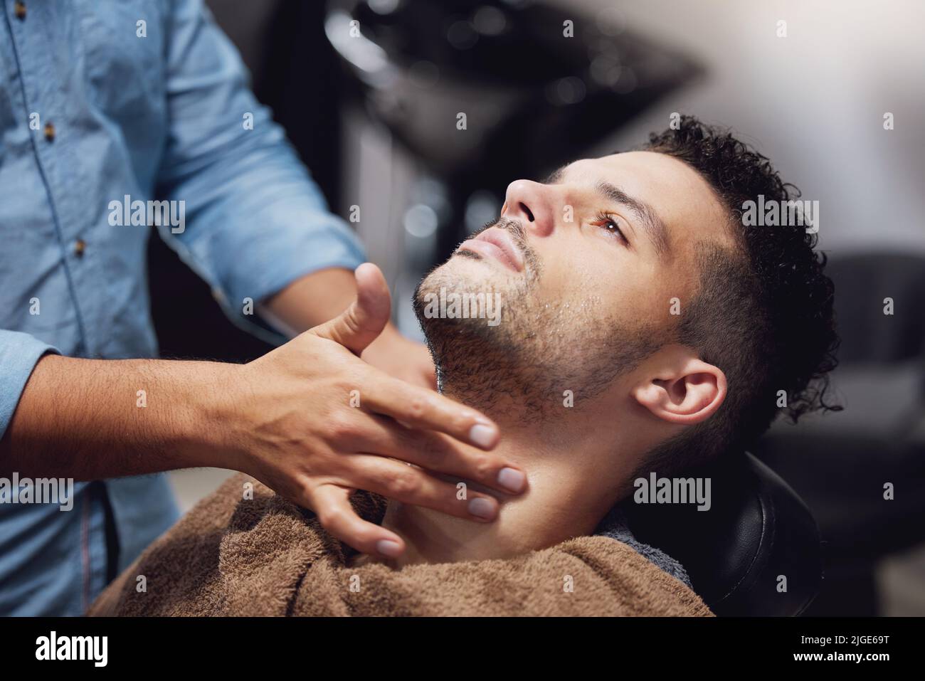 Er reinigt gut. Ein hübscher junger Mann, der von einem Friseur gepflegt wird. Stockfoto