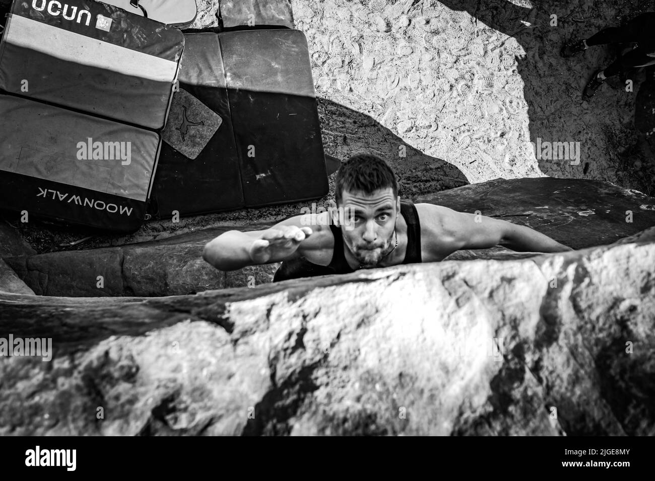 Kletterer springt zum oberen Halt des dynamischen Sprungboulders. Stockfoto