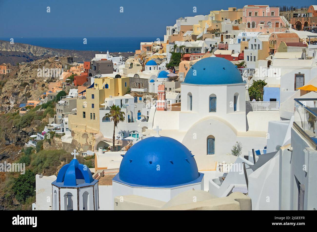 Oia, oder Ia ein malerisches Dorf mit weiß getünchten Häusern und blau gewölbten Kirchen auf der Insel Santorini, Teil der griechischen Kykladen-Inseln. Stockfoto