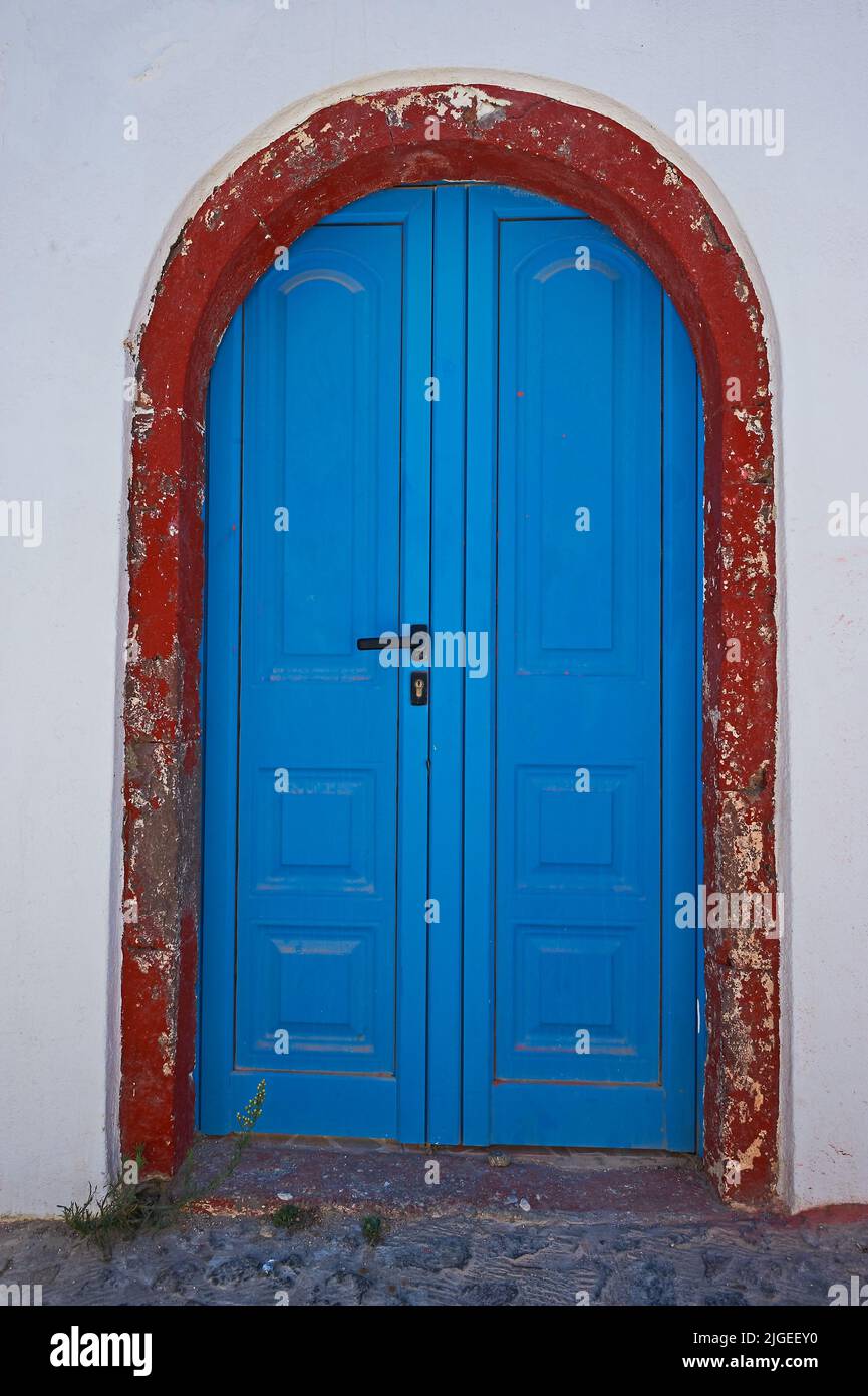 Oia und eine blaue Tür, eingerahmt von einem roten Steinbogen, in einem weiß getünchten Haus auf der Insel Santorini, einem Teil der Kykladen-Inseln vor dem griechischen Festland Stockfoto