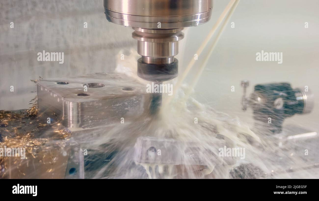 Nahaufnahme-Bohrmaschine mit Wasserspritzern und vielen metallischen Spießen. Nahaufnahme cnc-Bearbeitungszentrum Fräsen mit Kühlmittel. Stockfoto