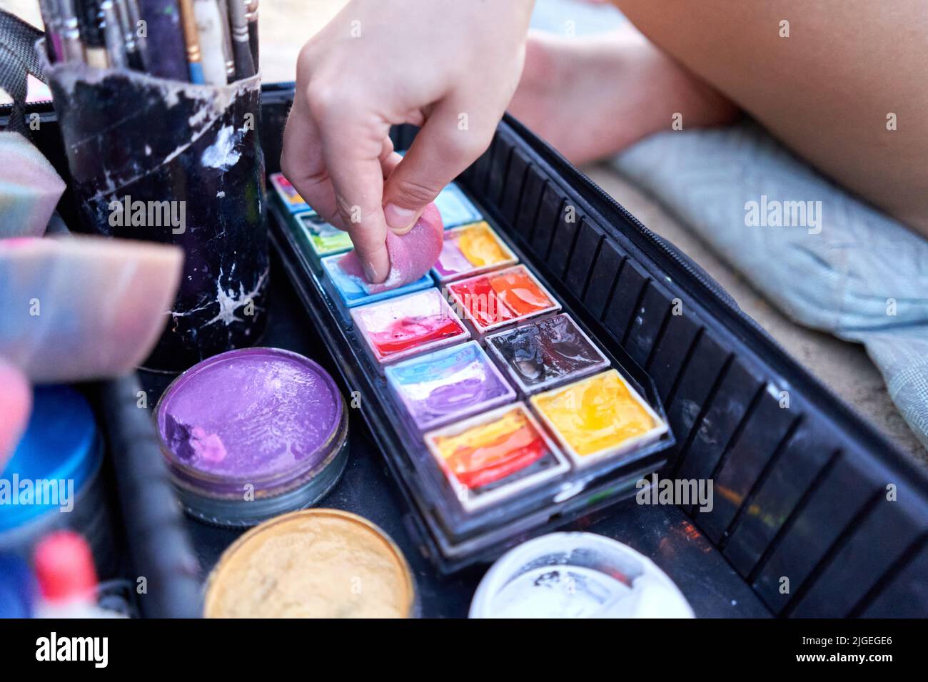 Künstler taucht ein Stück Schaum mit Farben, um eine Körperfarbe zu arbeiten. Stockfoto