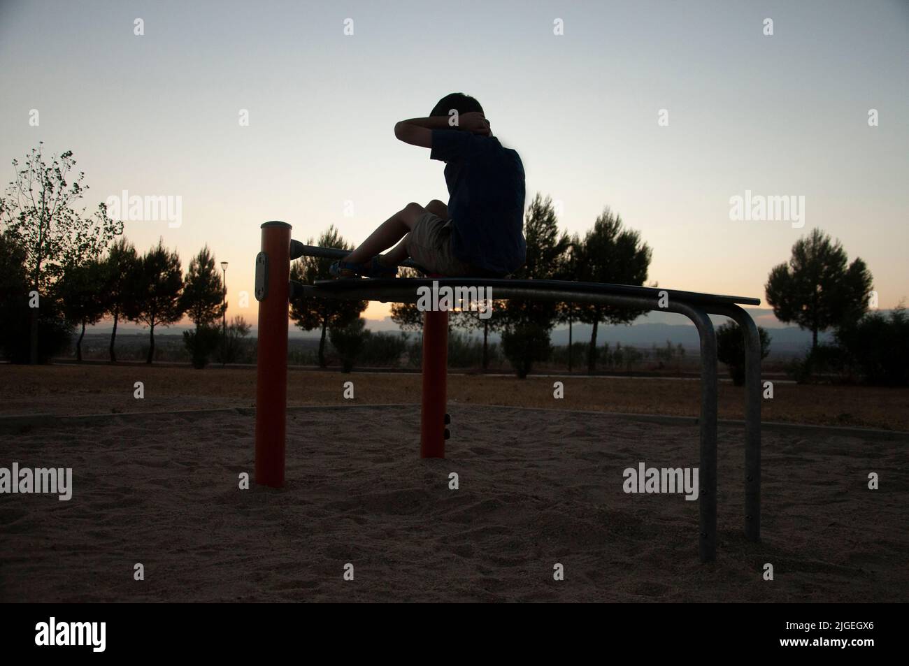 Youngster Silhouette tun ABS-Übung auf dem Park bei Sonnenuntergang. Kind, Kind trainieren Stockfoto