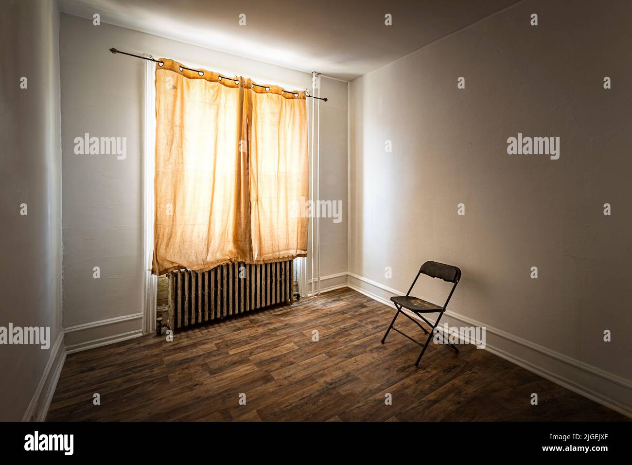 Vergilbter Vorhang in einem heruntergekommenen Zimmer mit einarmigtem Stuhl Stockfoto