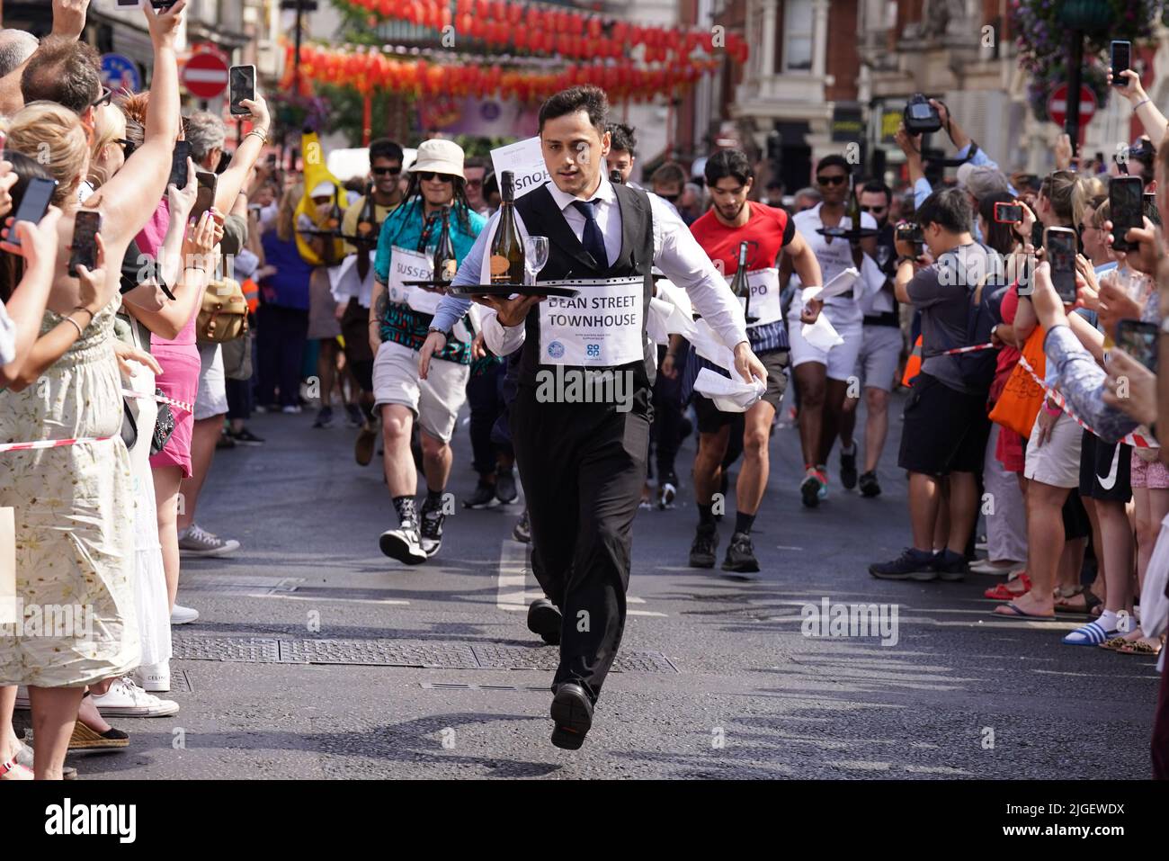 Die Menschen nehmen am Soho Waiter's Race im Soho Village Fete, Wardour Street, London, Teil. Eine Hundeschau, ein Spaghetti-Fressen-Wettbewerb und ein Kriegsschlepper der Polizei gegen die Feuerwehr sind alle Teil der Festivites auf dem Fete. Bilddatum: Sonntag, 10. Juli 2022. Stockfoto