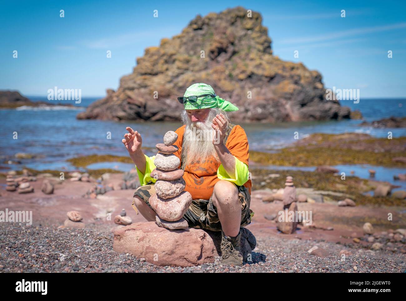 Der Kalifornier Stooert Flores nimmt an der "Zeitbalance"-Veranstaltung der European Stone Stacking Championships 2022 am Eye Cave Beach in Dunbar, East Lothian, Teil. Die Meisterschaften sind Europas größter Wettbewerb für alle Liebhaber und Künstler des Steinstapelns und des Felsausgleichs. Bilddatum: Sonntag, 10. Juli 2022. Stockfoto