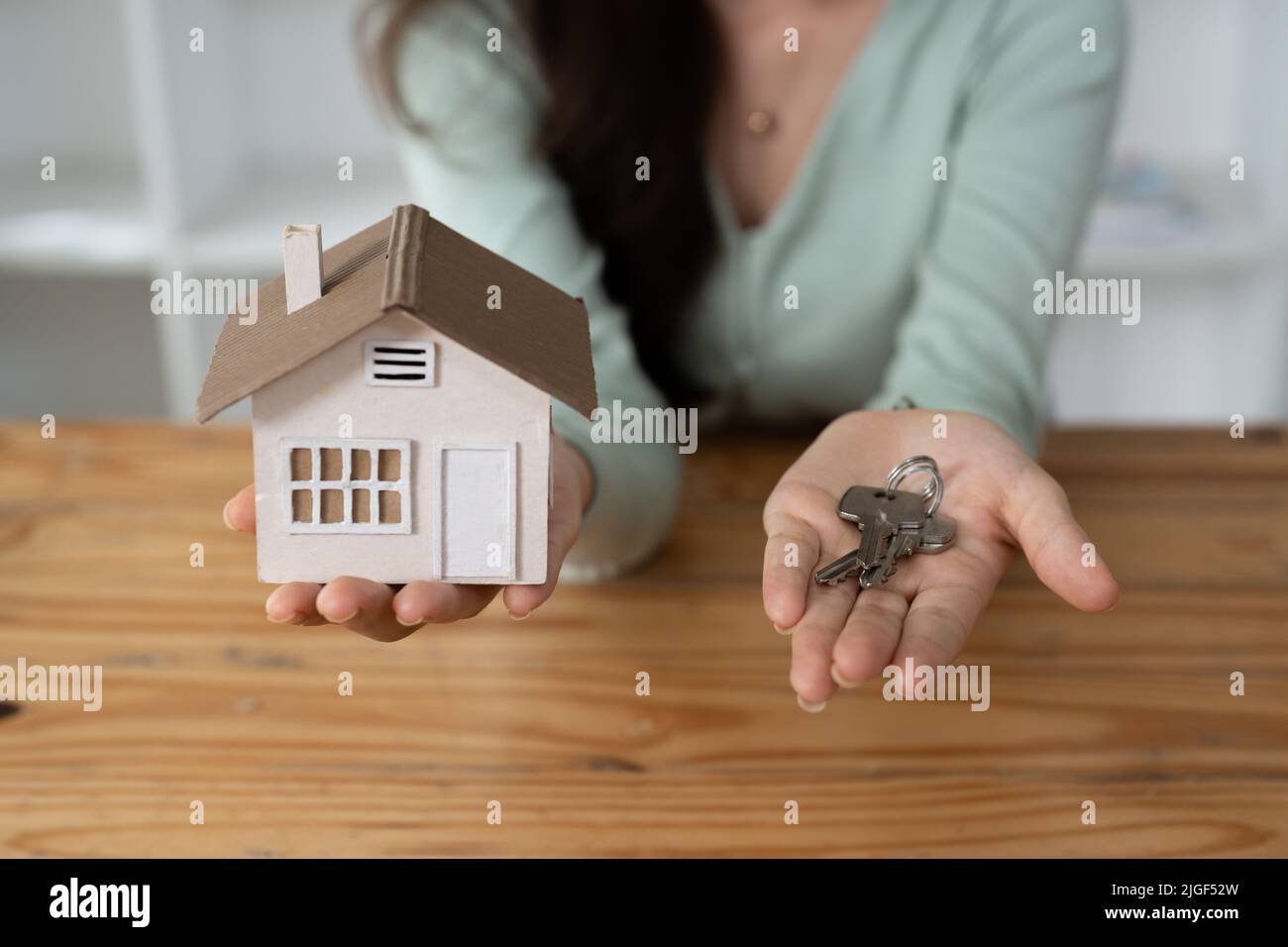 Close up Hand des Immobilienmaklers Übergabe der Schlüssel zu Hause Modell, Konzept für den Verkauf oder Umzug nach Hause Stockfoto