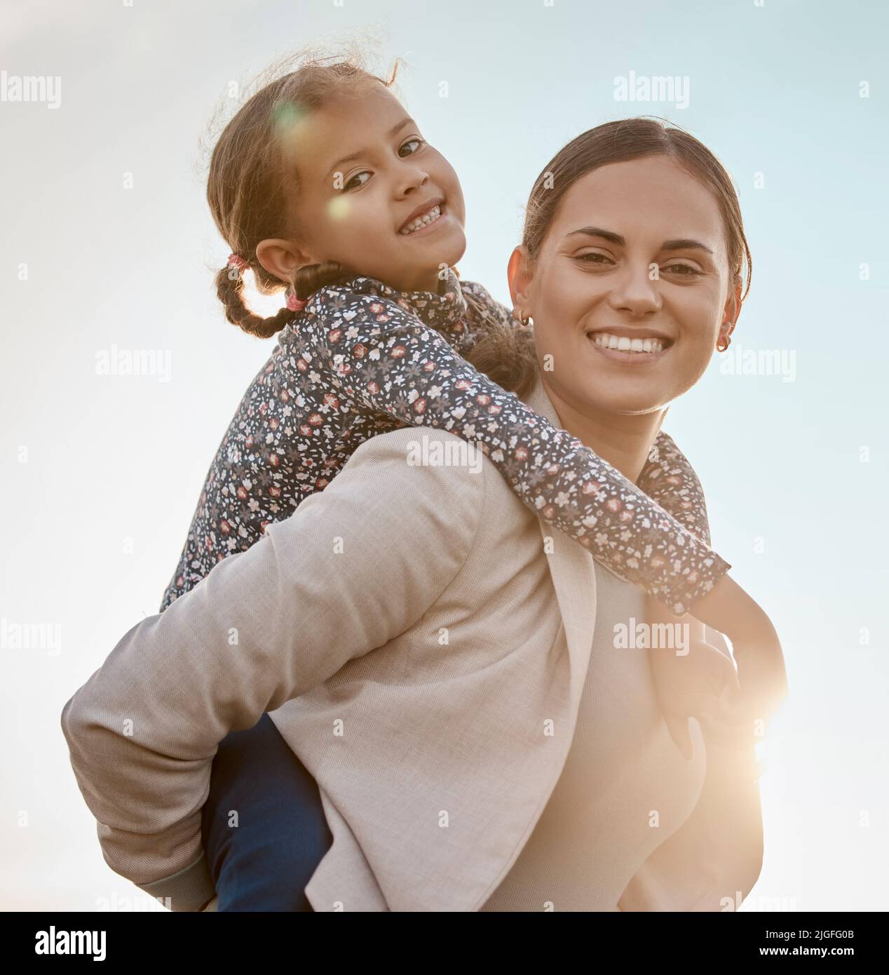 Möge sie sich immer so an uns erinnern. Ein entzückendes kleines Mädchen, das mit ihrer Mutter auf ihrem Bauernhof eine Huckepack-Fahrt genießt. Stockfoto