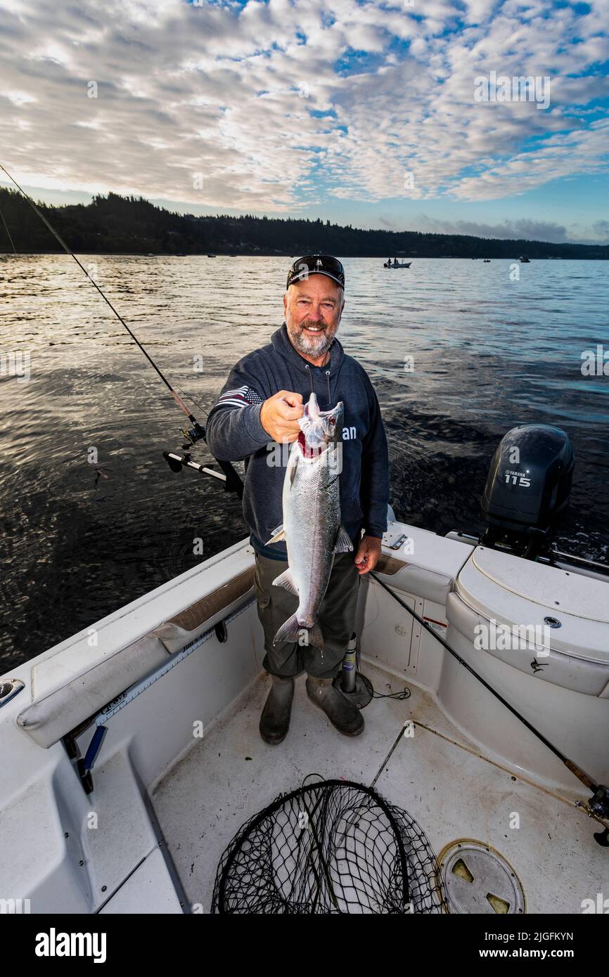 WA20630-00....WASHINGTON - Jim Johansen hält einen Silberlachs hoch, den er beim Trolling im Puget Sound gefangen hat. HERR# J5 Stockfoto