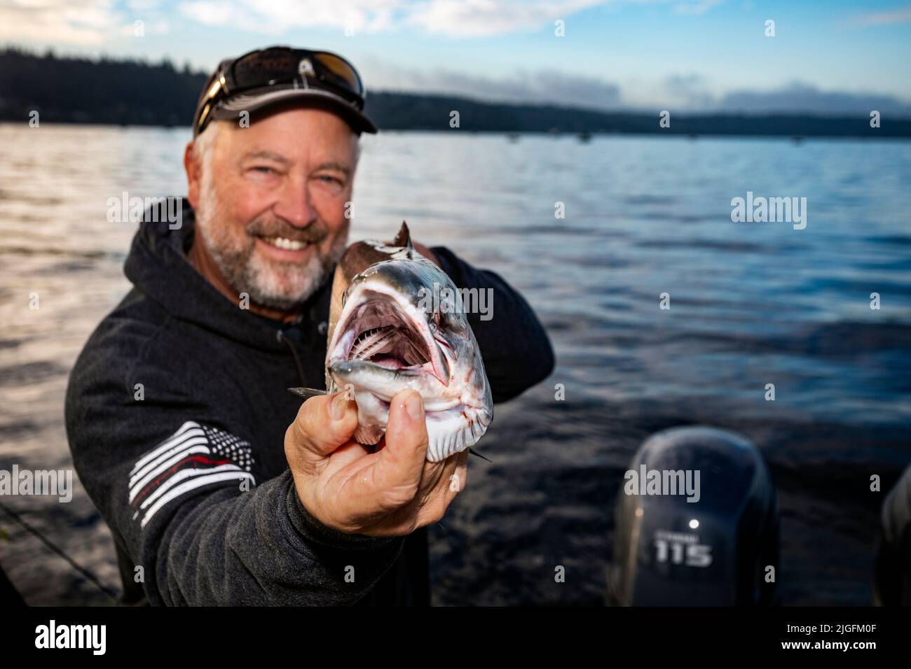 WA20631-00....WASHINGTON - Jim Johansen hält einen Silberlachs hoch, den er beim Trolling im Puget Sound gefangen hat. HERR# J5 Stockfoto