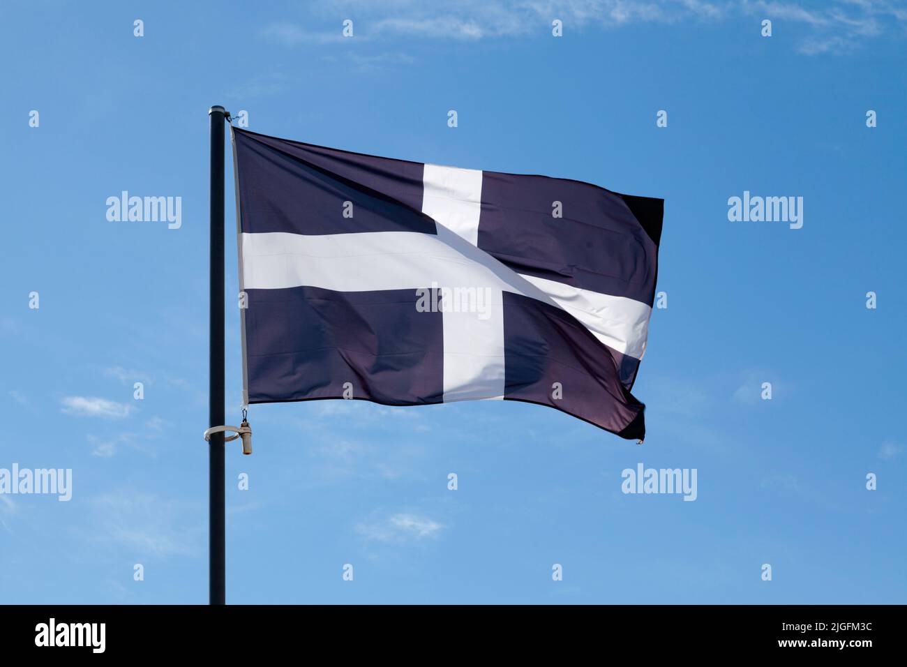 Die Flagge des Heiligen Piran (Cornwall) winkt auf dem Pol gegen einen blauen Himmel. Stockfoto