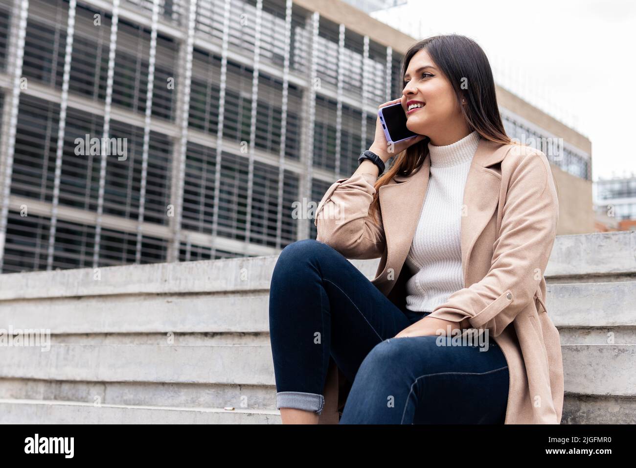 Eine junge, lateinische Frau telefoniert draußen Stockfoto