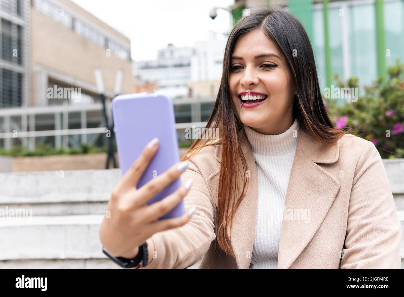 Eine junge, lateinische Frau mit Brille ist überrascht, wenn sie auf das Telefon schaut Stockfoto