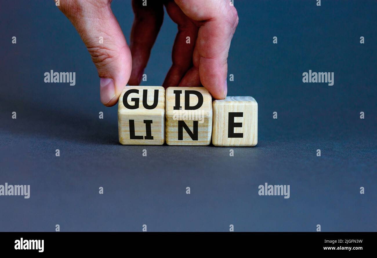 Richtungssymbol. Konzept Wort Richtlinie auf Holzblöcken. Geschäftsmann Hand ändert Wörter Guide on Line. Schöne graue Tabelle grauen Hintergrund. Unternehmen Stockfoto